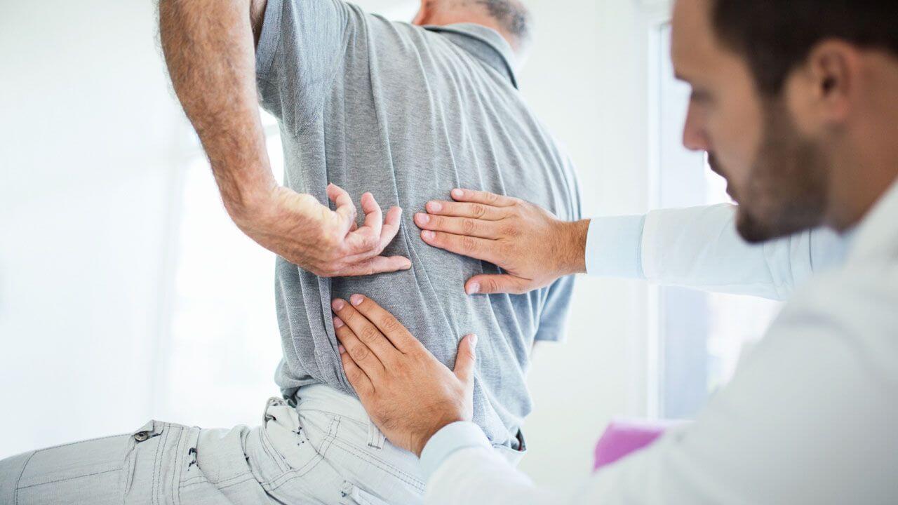 Doctor examining patient who is pointing out where they are having pain in their back