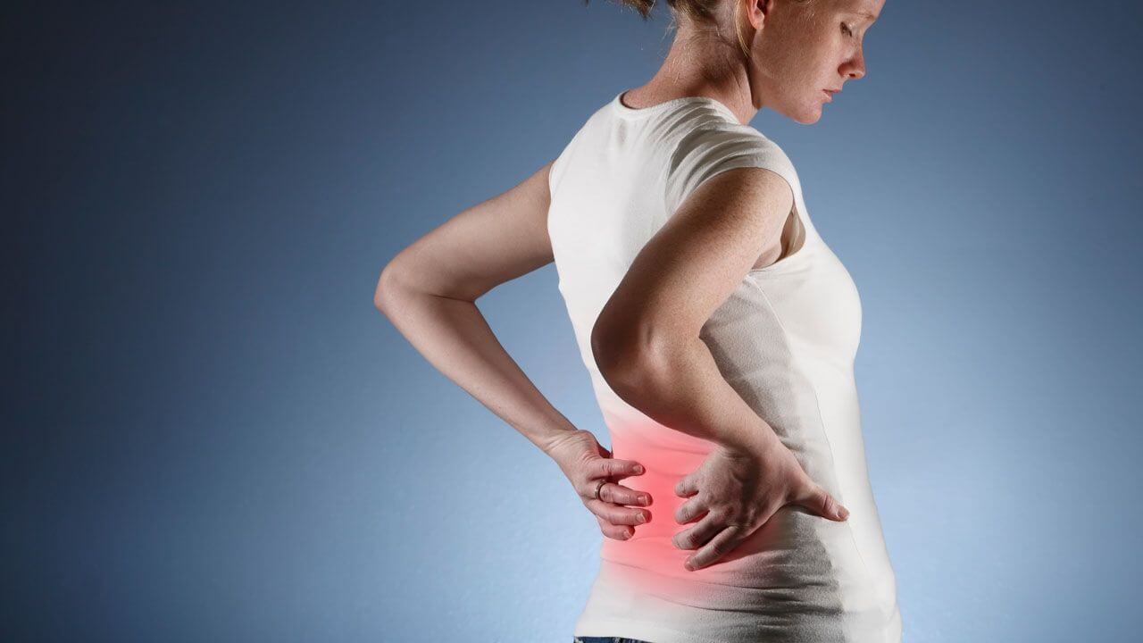 Woman rubbing her lower back which has a highlighted area of pain