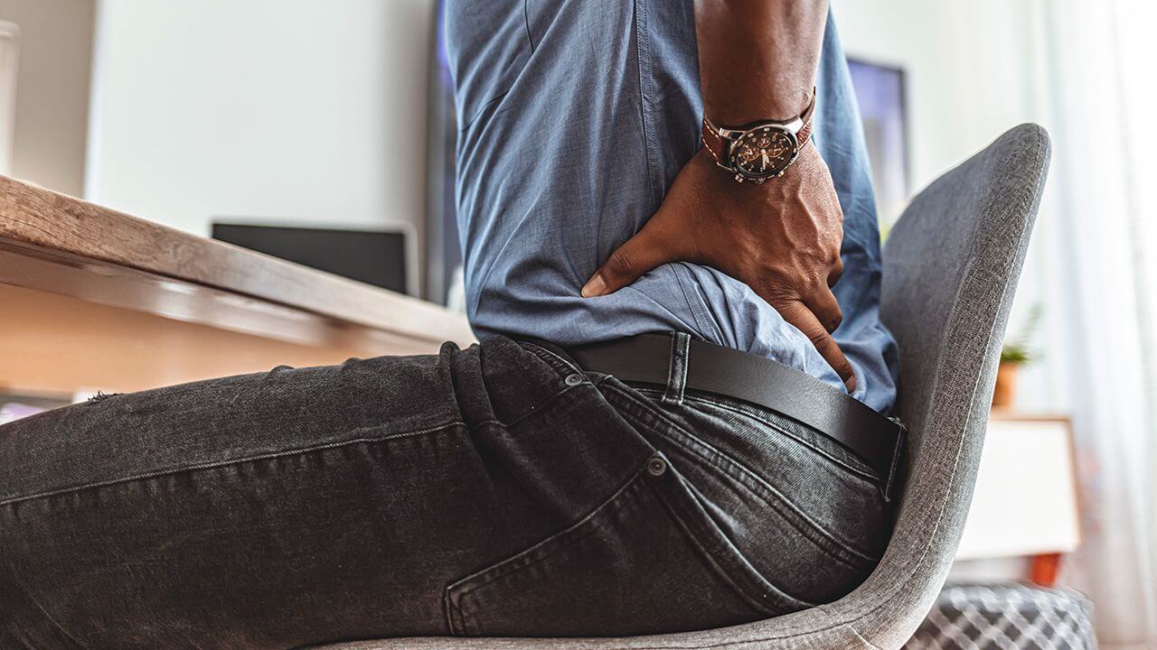 Man sitting and gripping his back in pain