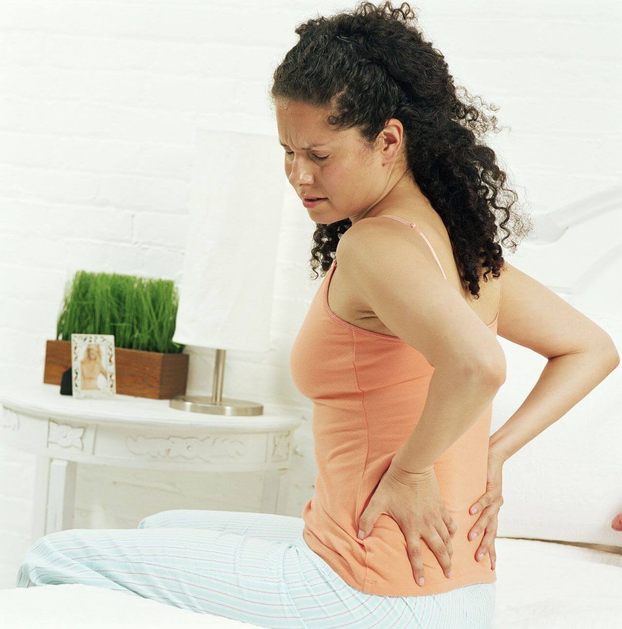 Woman pressing her hands against her back in pain