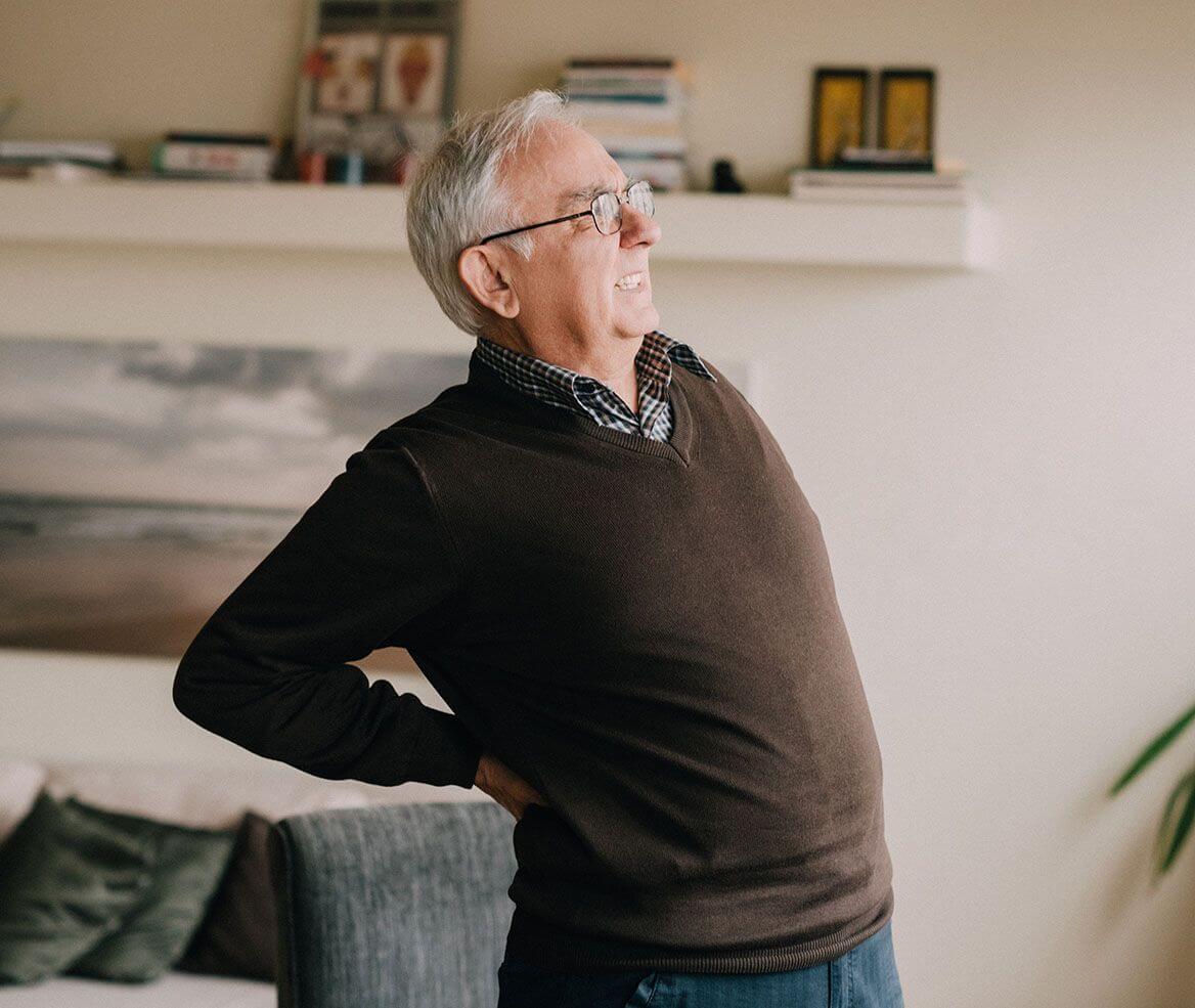 Older man pressing against his back from pain